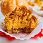 A photo of 1 keto pumpkin spice cheesecake bites arranged on a table, with some whipped cream and cinnamon on top. The photo has a light white background and a small pumpkin on the side. The photo looks appetizing and festive