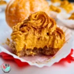 A photo of 1 keto pumpkin spice cheesecake bites arranged on a table, with some whipped cream and cinnamon on top. The photo has a light white background and a small pumpkin on the side. The photo looks appetizing and festive