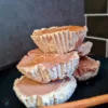 Twelve Keto Gingerbread Cheesecakes on a black plate with a cinnamon stick on the side.