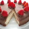 A delicious keto chocolate cake adorned with fresh strawberries and cream, a slice revealing the moist layers within.