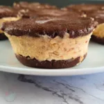 A close-up view of Keto Chocolate Peanut Butter Ice Cream Sandwiches with a rich chocolate top and creamy peanut butter ice cream middle, arranged on a white plate.