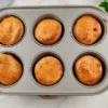 A top view of six golden brown Yorkshire puddings made with almond flour, sitting in a grey baking tray, showcasing a gluten-free option for this classic dish.