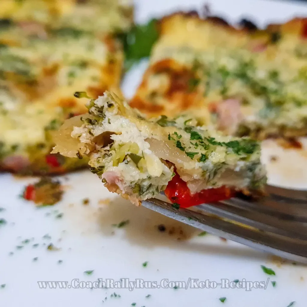 A close-up view of a Keto Cottage Cheese Frittata with Pancetta and Broccoli, with a bite on a fork showing the fluffy texture and colorful ingredients, served on a white plate with a garnish of herbs.