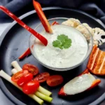 A creamy and inviting bowl of Keto Ranch Dip with Cottage Cheese, garnished with fresh herbs, ready to be enjoyed with a colorful selection of vegetable sticks.