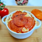 Delicious keto-friendly Cottage Cheese Pizza Bowl topped with savory pepperoni slices, garnished with fresh herbs, and served in a white bowl on a rustic wooden table, ready to enjoy.