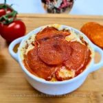 Keto-friendly Cottage Cheese Pizza Bowl topped with pepperoni slices, garnished with fresh herbs, and served in a white bowl on a rustic wooden table, ready to enjoy.