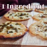 Golden-brown cottage cheese chips seasoned with green herbs, presented on a rustic wooden surface, highlighting the simplicity of the one-ingredient recipe from CoachRallyRus.com’s keto collection.