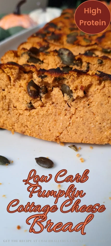 A vertical image showcasing a loaf of Keto Cottage Cheese Pumpkin Bread with a slice cut out, revealing its moist texture and pumpkin seeds on top. The bread is placed on a white surface with the text “High Protein” at the top and “Low Carb Pumpkin Cottage Cheese Bread” in bold red letters at the bottom. A blurred background hints at more of the loaf and a whole pumpkin, emphasizing the bread’s main ingredient.