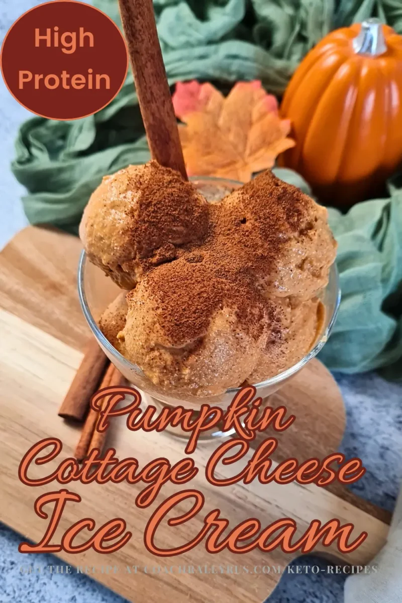 A glass bowl filled with Pumpkin Cottage Cheese Ice Cream topped with a sprinkle of cinnamon, resting on a wooden surface. A small orange pumpkin and green leaves are in the background, emphasizing the autumn theme. The text ‘High Protein’ is prominently displayed at the top, with ‘Pumpkin Cottage Cheese Ice Cream’ written below it in decorative font, indicating that this is a high-protein keto dessert option.