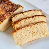 A freshly baked loaf of keto-friendly Cottage Cheese Bread with Almond Flour, showcasing a golden-brown crust and a soft, airy interior, served on a white plate.