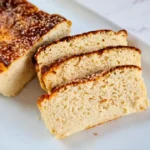 A freshly baked loaf of keto-friendly Cottage Cheese Bread with Almond Flour, showcasing a golden-brown crust and a soft, airy interior, served on a white plate.