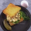 Overhead view of keto cottage cheese dill pickle egg salad served on toasted bread with fresh dill and a whole pickle.