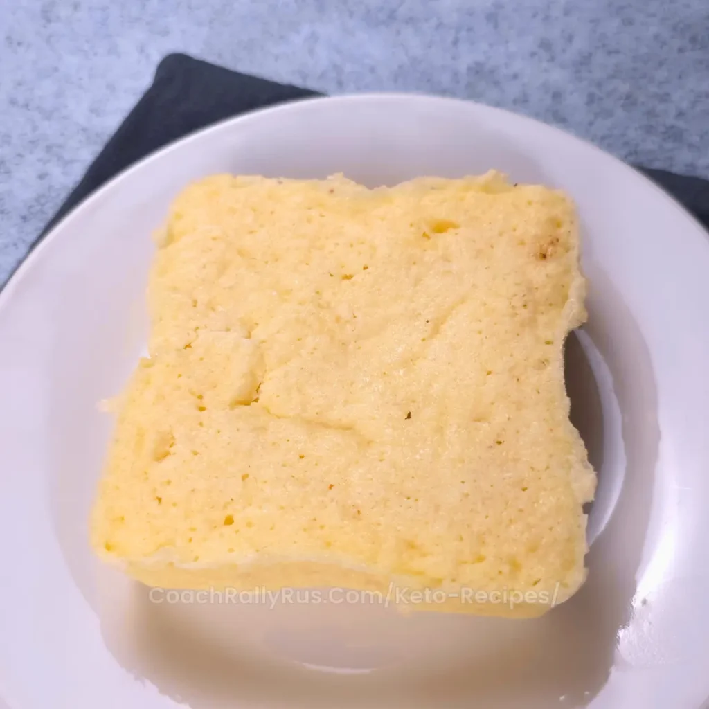 Keto cottage cheese mug bread, uncut and fresh on a white plate.