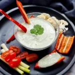 A creamy and inviting bowl of Keto Ranch Dip with Cottage Cheese, garnished with fresh herbs, ready to be enjoyed with a colorful selection of vegetable sticks.