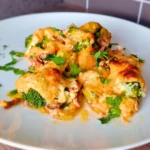 Cheesy keto ground beef and broccoli casserole on a white plate, topped with golden melted cheese and fresh parsley.