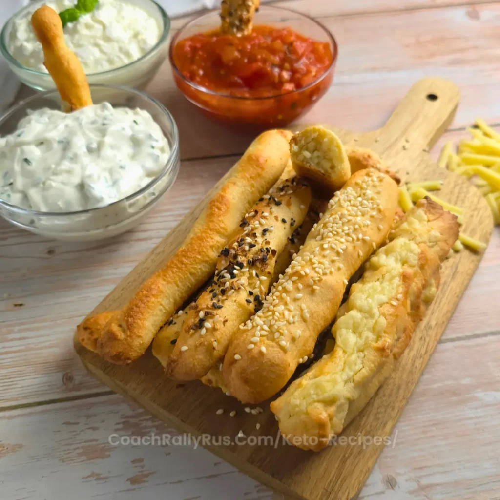 Golden-brown keto breadsticks with sesame and bagel seasoning, served with marinara sauce.