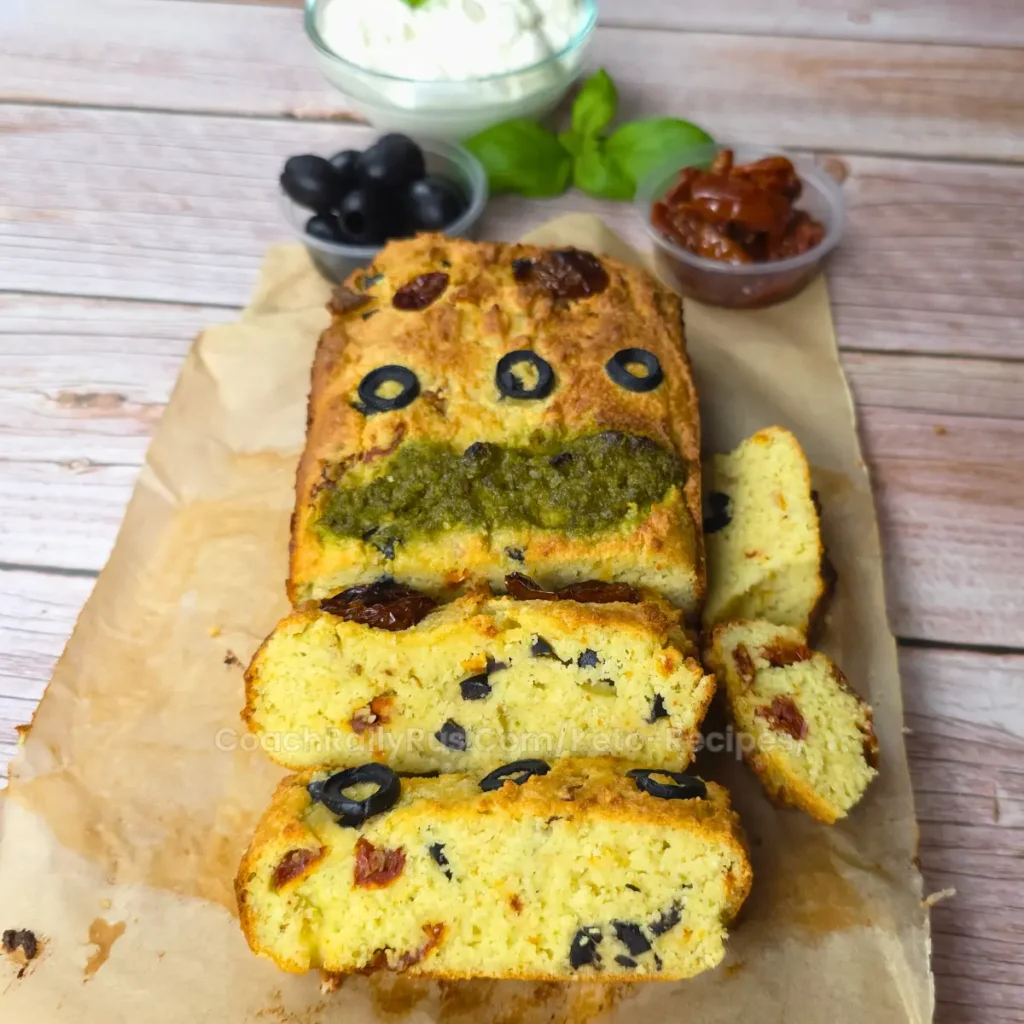 Freshly baked keto cottage cheese bread with sun-dried tomatoes and olives on parchment paper.