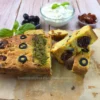 Close-up of keto sun-dried tomato and olive cottage cheese bread served with cottage cheese, olives, and basil.