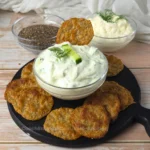 Keto Chia Seeds Cottage Cheese Chips on a black serving board with a bowl of cottage cheese dip and chia seeds.