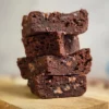 A stack of keto cottage cheese brownies showing a gooey texture.