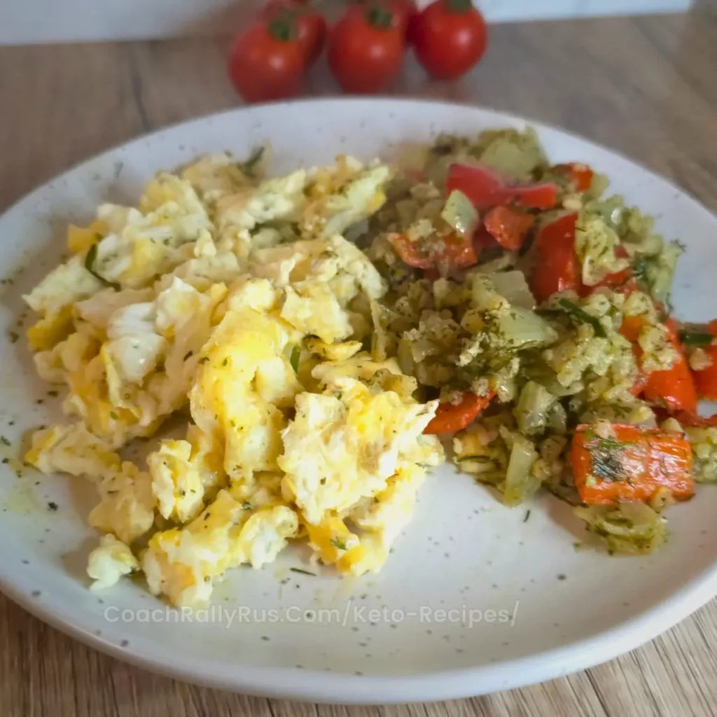 Scrambled eggs served with sautéed cauliflower rice and bell peppers on a plate.