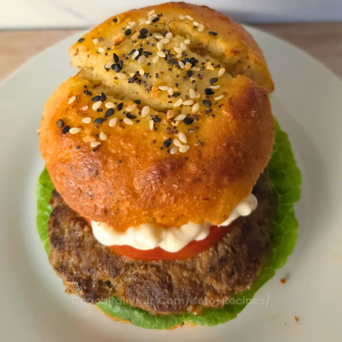 Keto burger made with egg free cottage cheese keto bun, beef patty, lettuce, tomato, and mayo.