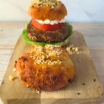 Keto burger served with egg free cottage cheese keto bun and an extra bun on a board.