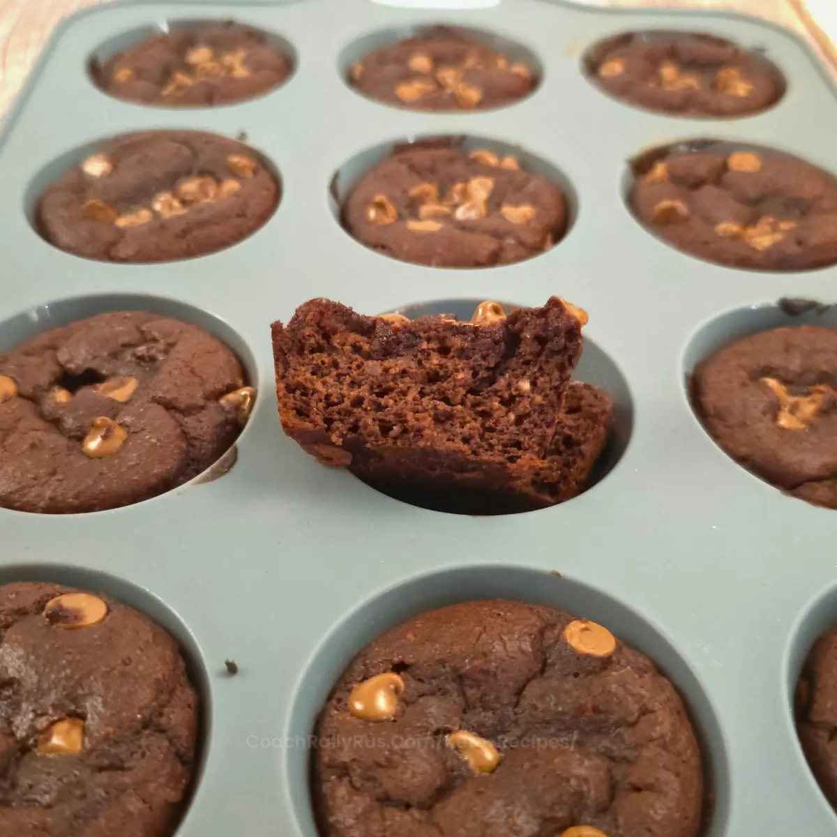 Freshly baked brownie muffins in a silicone tray with one cut open