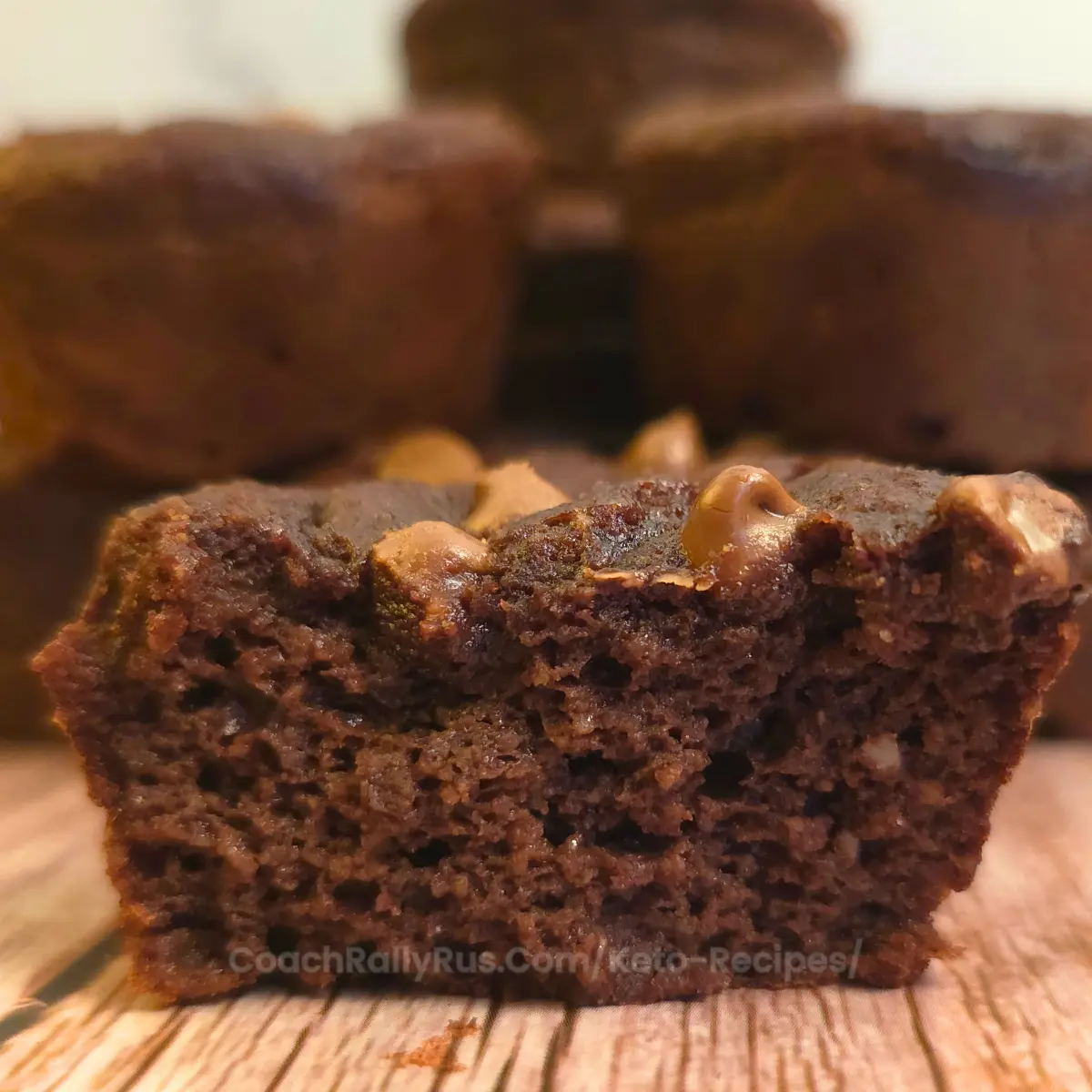 Soft keto brownie muffins made with cottage cheese, shown cooling in a non-stick tray with one muffin revealing its fudgy texture.