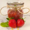 Glass jar filled with keto strawberry chia seed jam and fresh strawberries in front