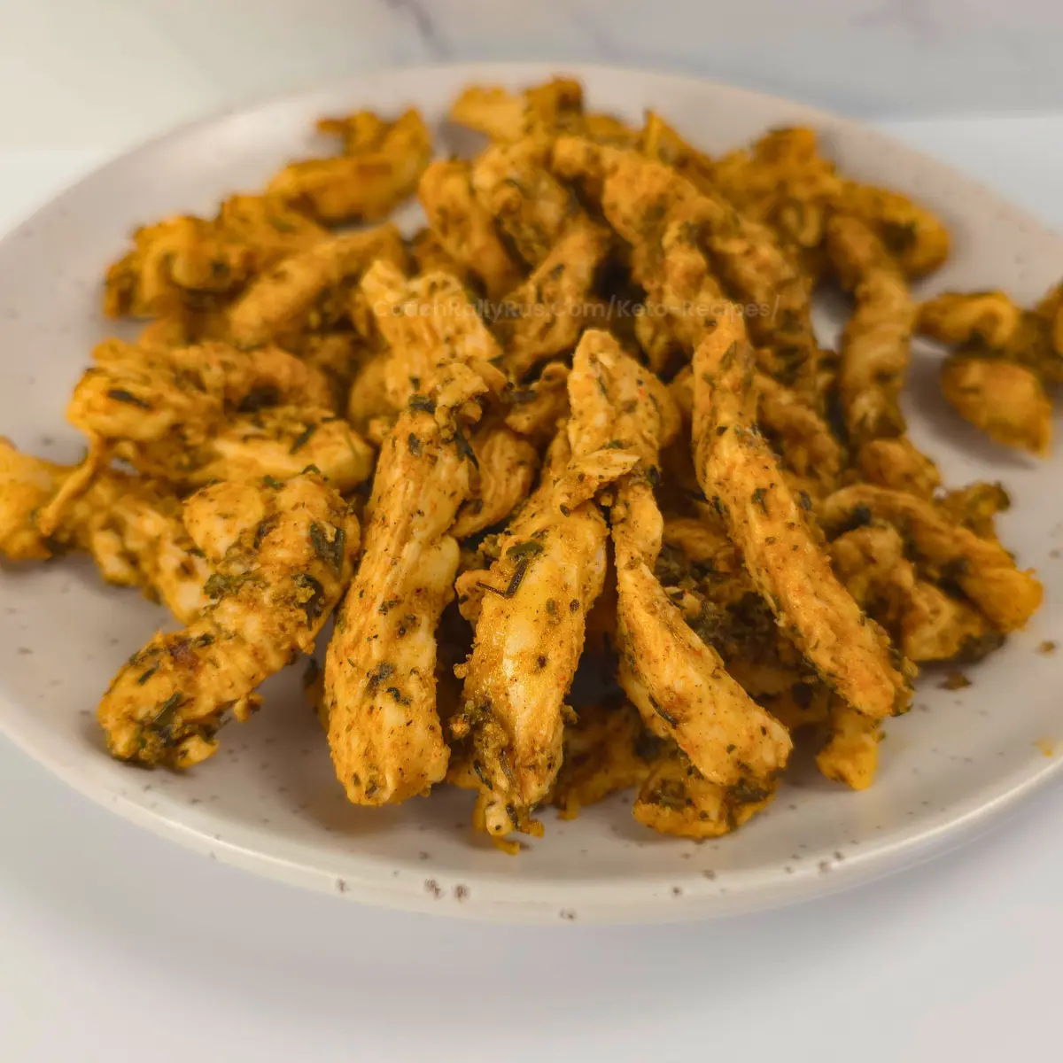 Sliced chicken gyros strips with Greek seasoning on a plate