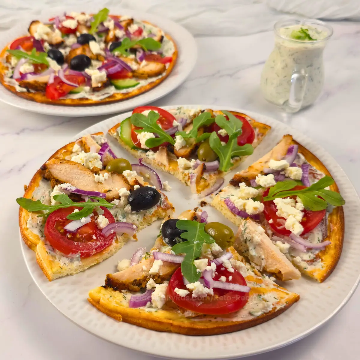 Keto flatbread pizza topped with chicken gyros, red onion, olives, and feta