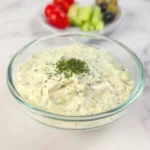 Creamy keto tzatziki sauce with sour cream in a glass bowl with garnish