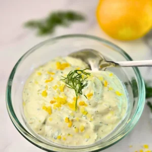 Creamy keto lemon dill cottage cheese sauce in a glass bowl with fresh dill and lemon zest