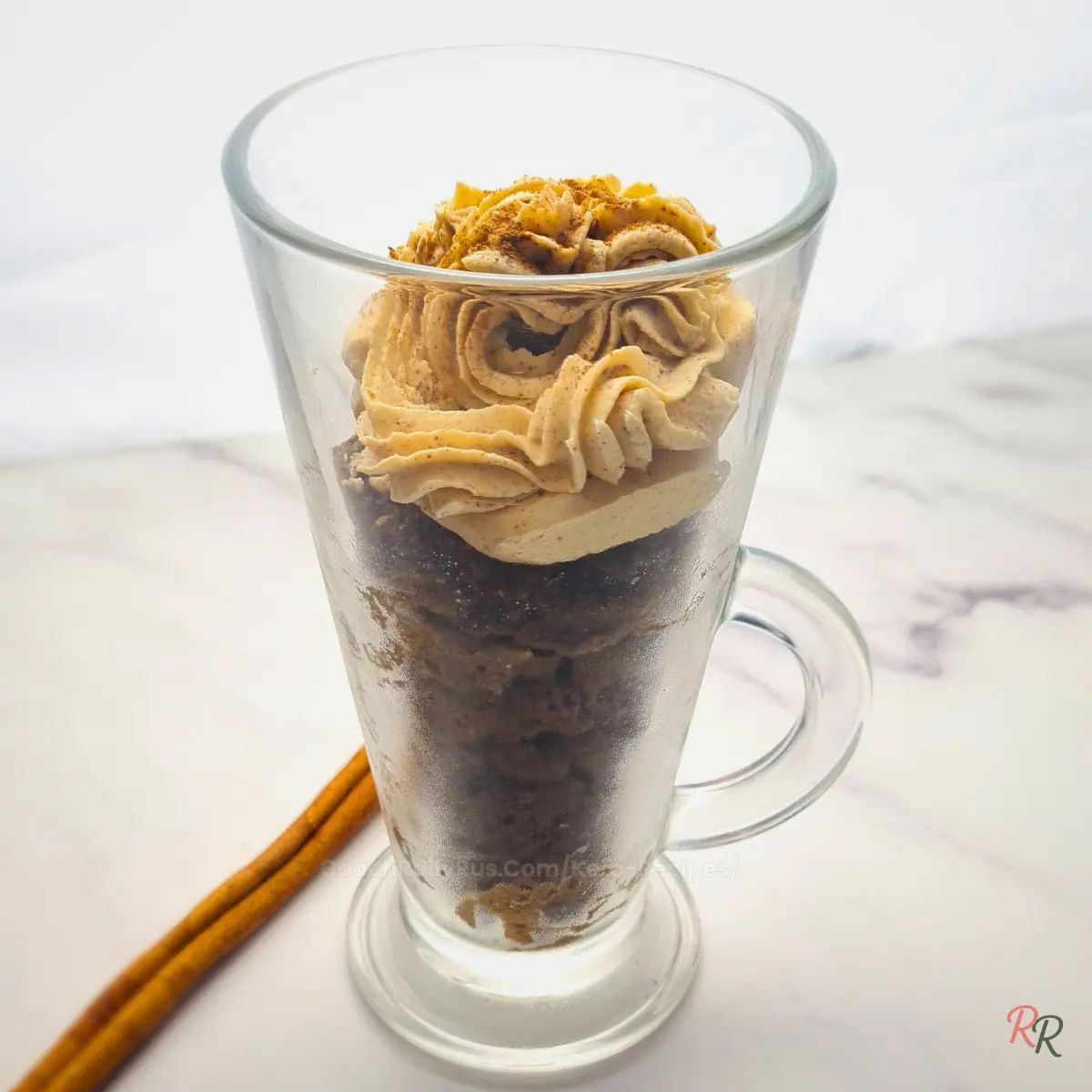 Pumpkin spice mug cake topped with whipped mousse in a glass mug