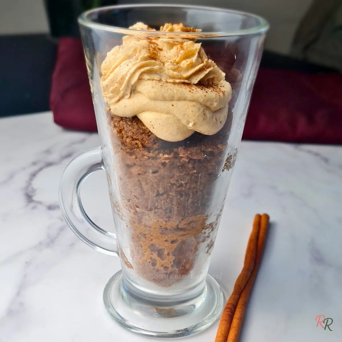 Keto espresso pumpkin mug cake in a tall latte glass with pumpkin mousse on top