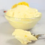Spoonful of creamy keto lemon cheesecake fluff in front of dessert bowl