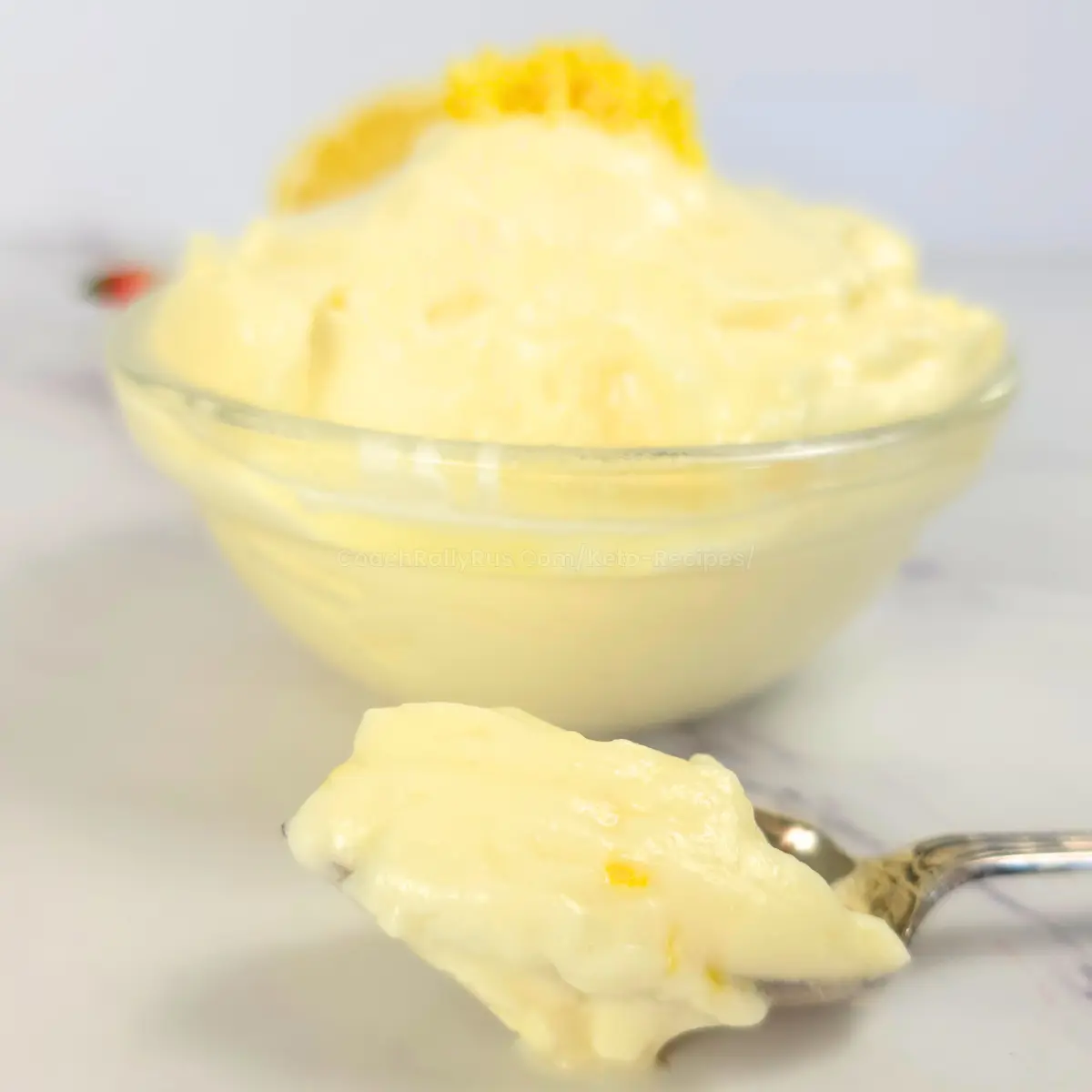 Sugar Free Keto Lemon Cheesecake Fluff Spoonful of creamy keto lemon cheesecake fluff in front of dessert bowl