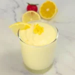 Keto lemon mousse in a glass topped with lemon zest and lemon wedge.