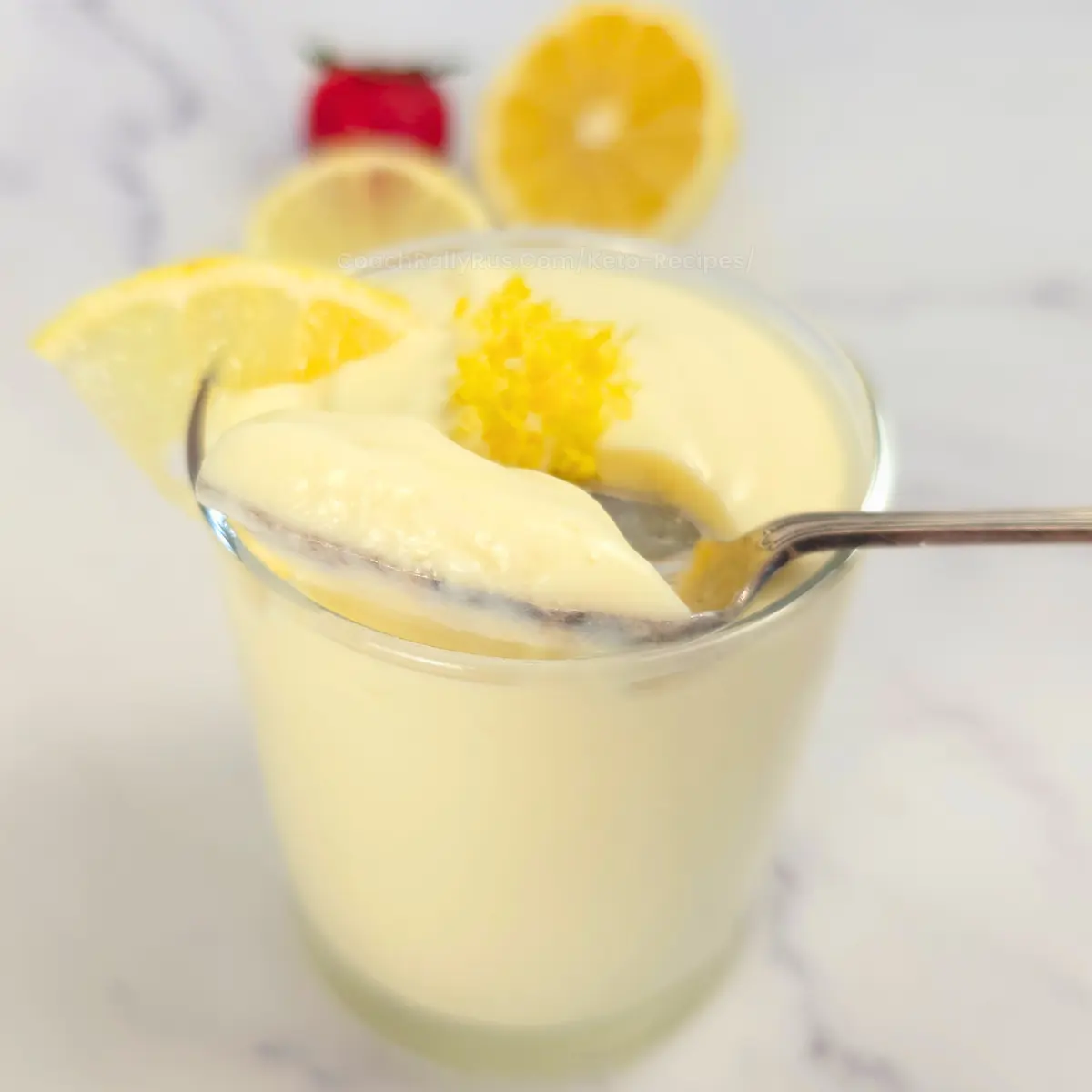 Spoon lifting thick lemon mousse from glass.