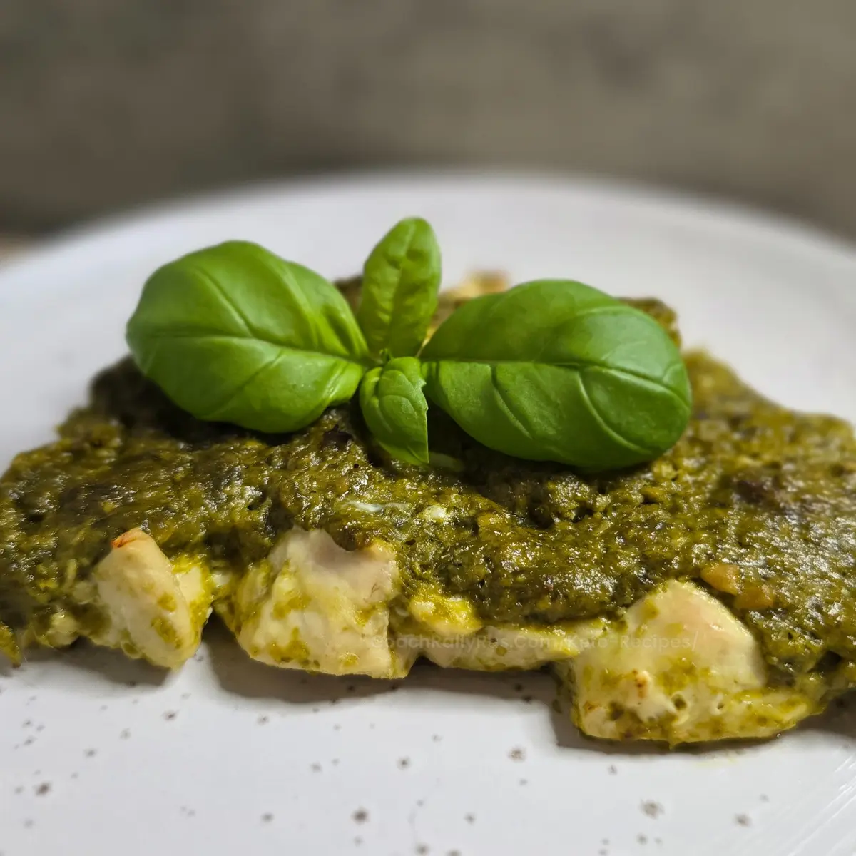 Baked keto pesto chicken topped with fresh basil