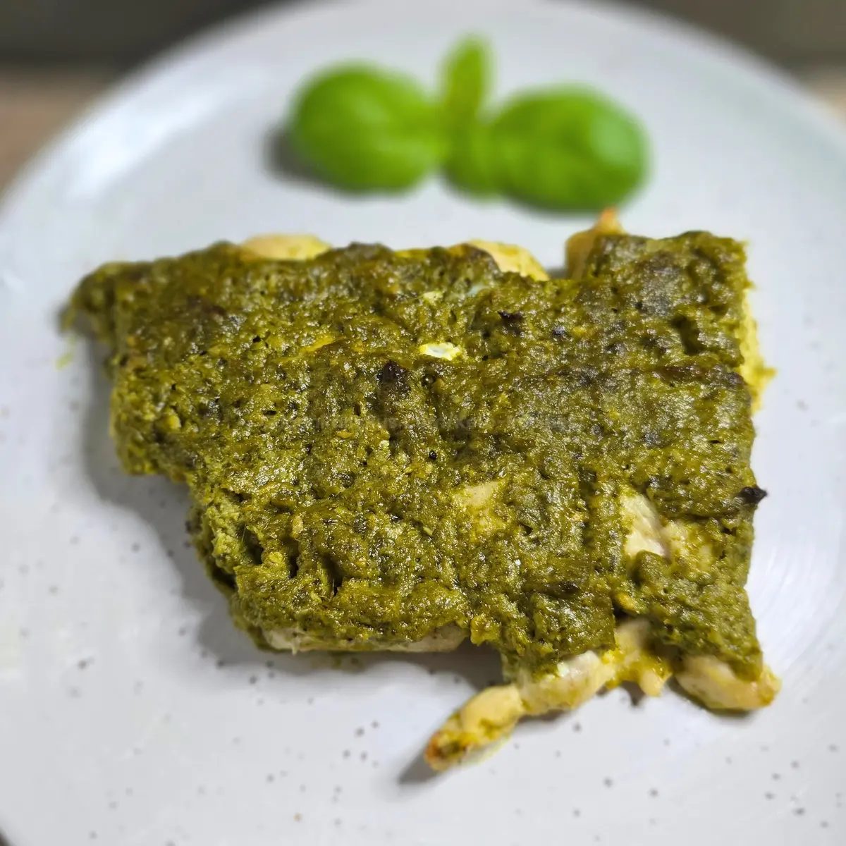 Overhead view of baked pesto chicken on white plate