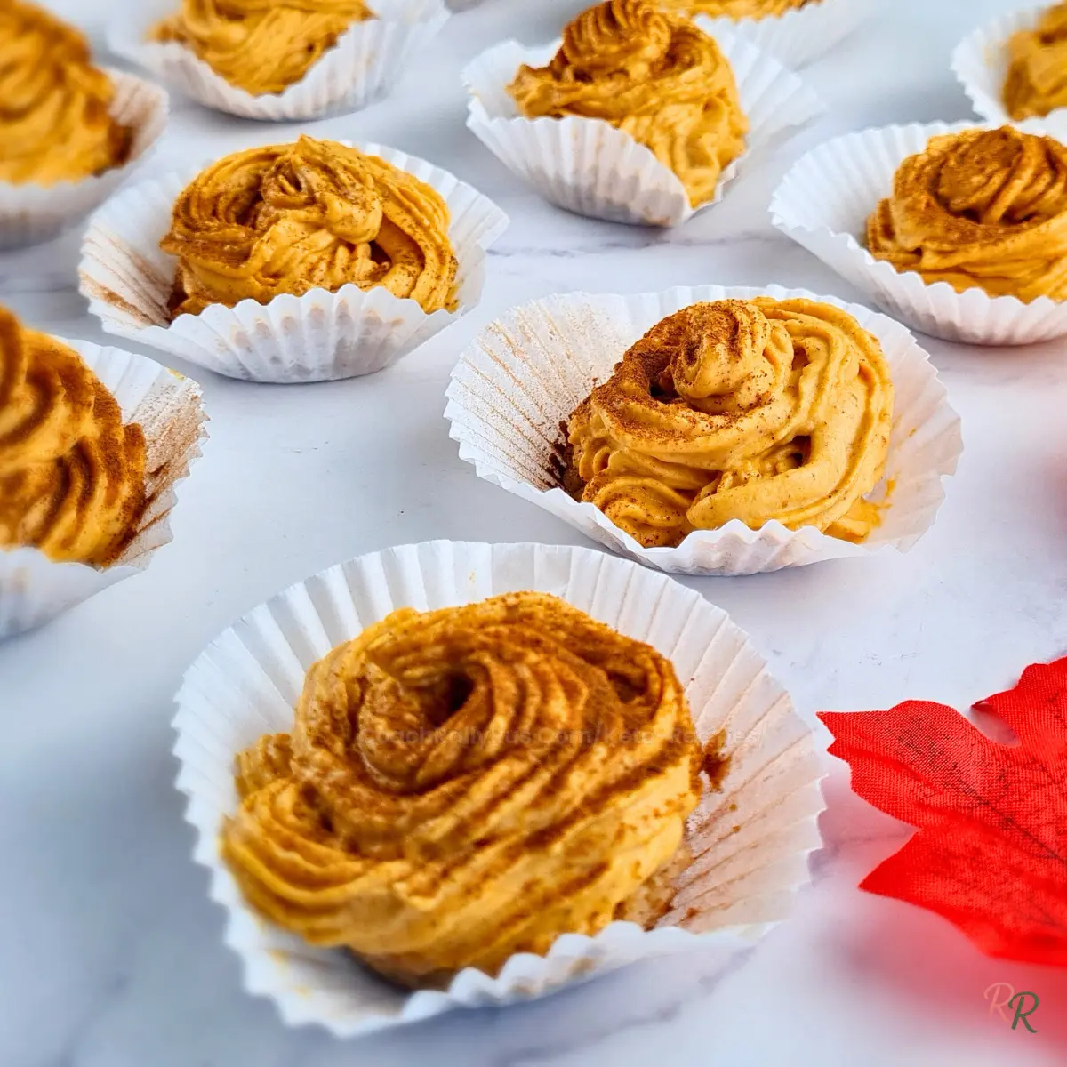 Overhead view of multiple keto pumpkin cheesecake bites arranged on marble background