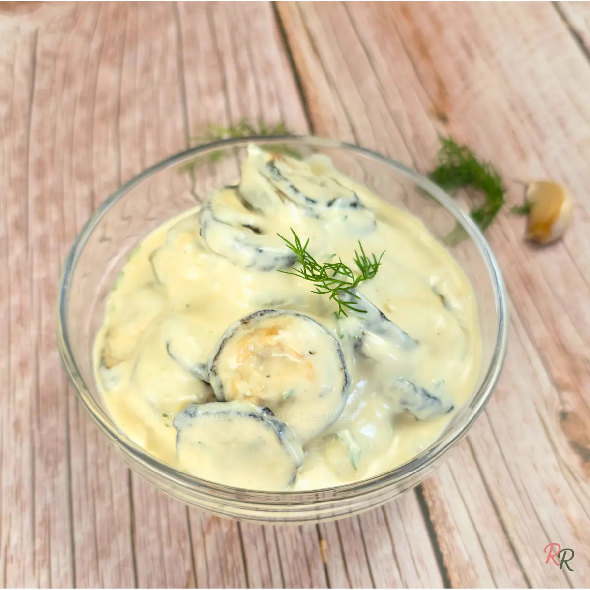 Roasted zucchini served with creamy Greek yogurt dip topped with fresh dill in a round glass bowl