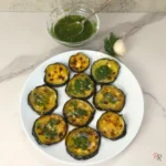 Flatlay of garlic dill roasted zucchini served on a white plate with extra sauce in a bowl.