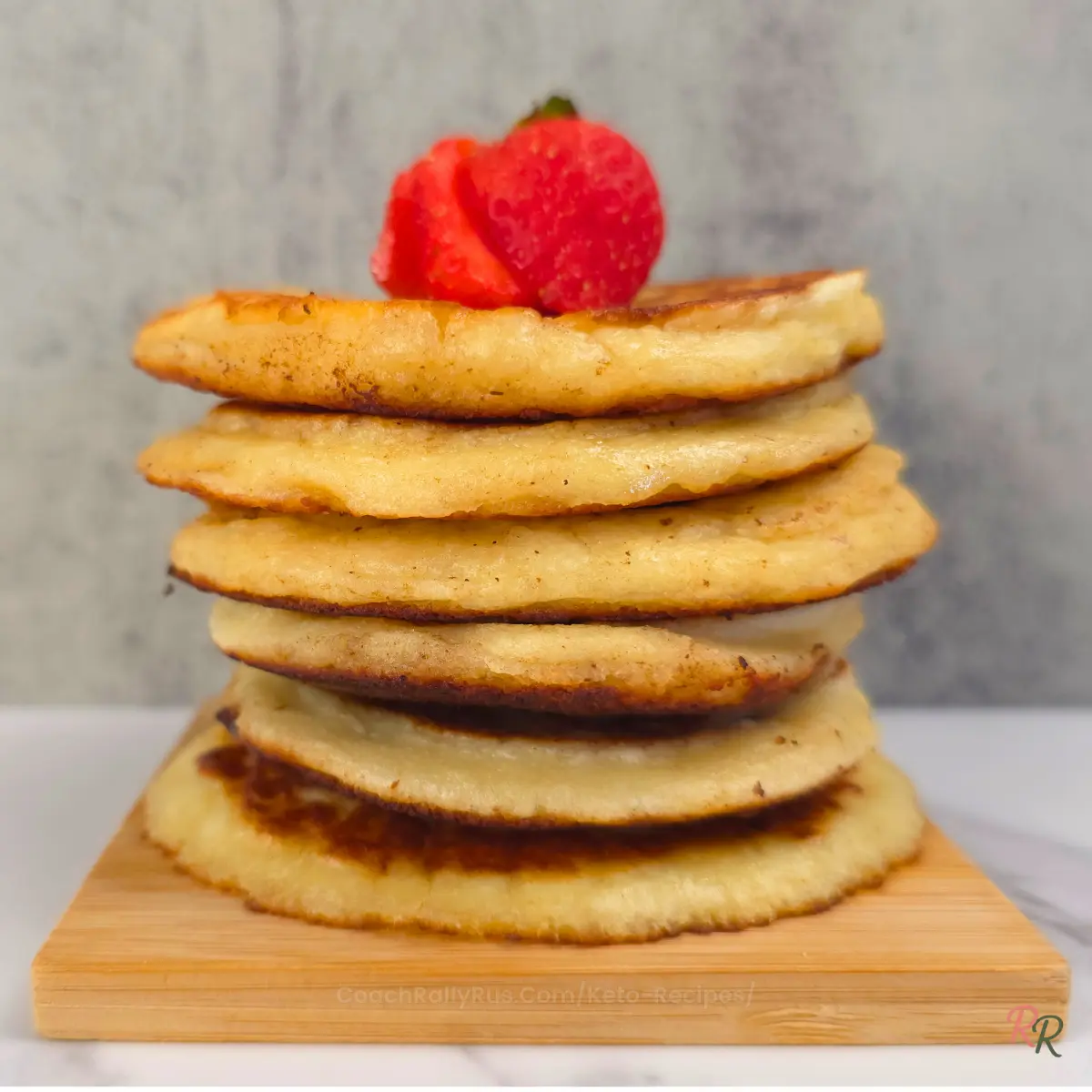 Stack of keto almond flour cottage cheese pancakes topped with fresh strawberry.