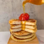 tack of almond flour cottage cheese pancakes topped with strawberry and drizzled with sugar free syrup.