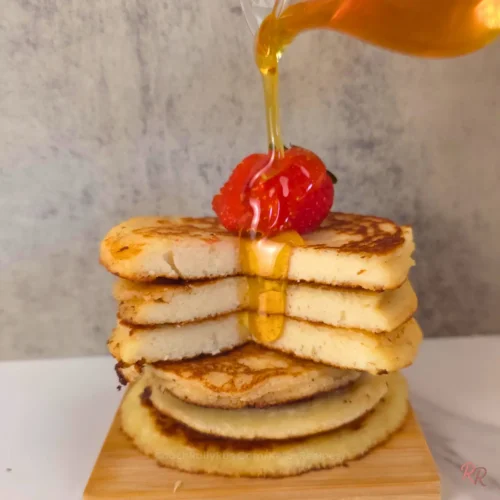 tack of almond flour cottage cheese pancakes topped with strawberry and drizzled with sugar free syrup.