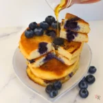 Keto blueberry pancakes with syrup and fresh blueberries on a plate