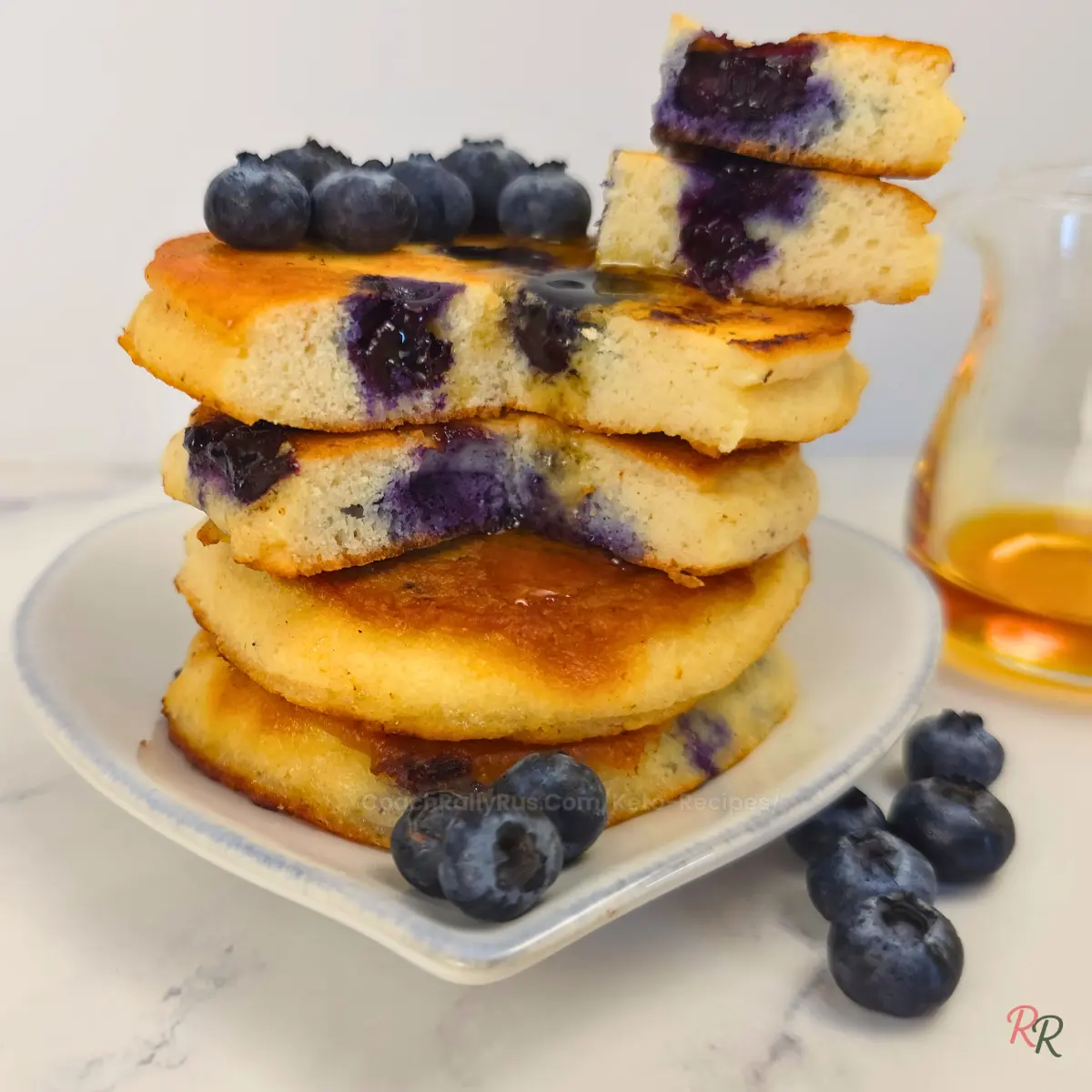 Low carb blueberry almond flour pancakes stacked with syrup and berries